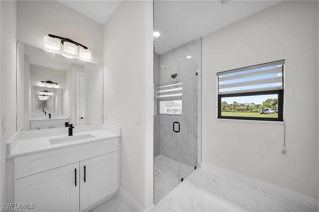 Bathroom featuring a marble finish shower, vanity, recessed lighting, and light marble finish flooring