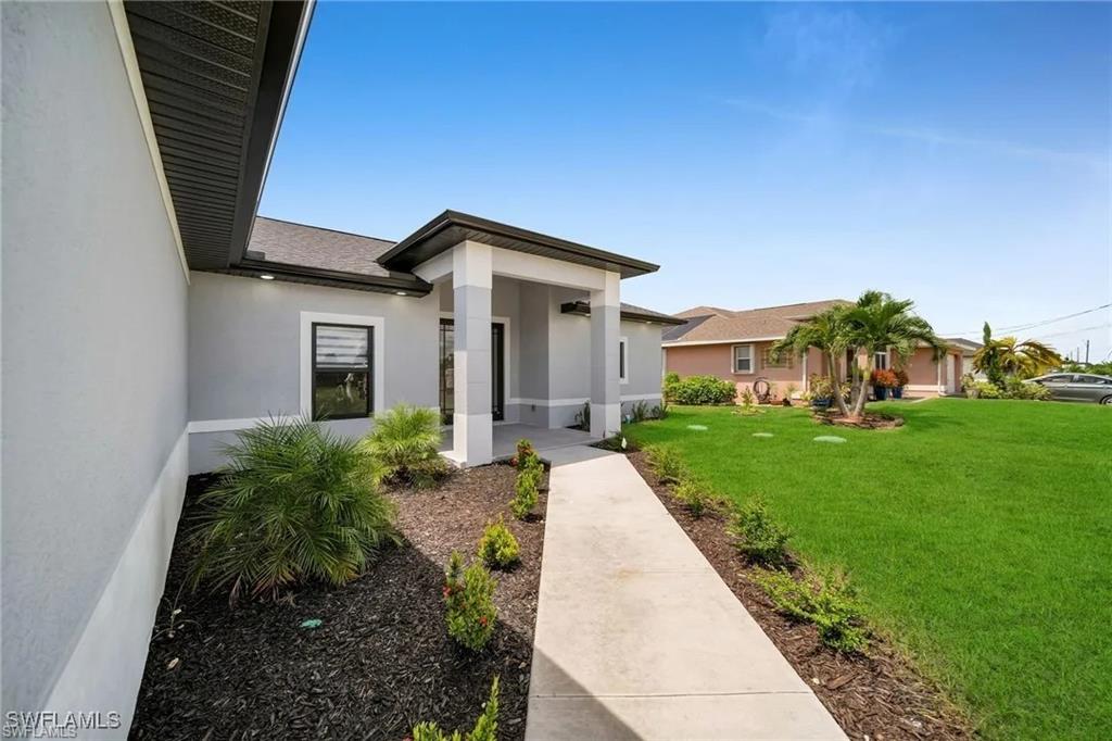 Property entrance featuring a yard and stucco siding