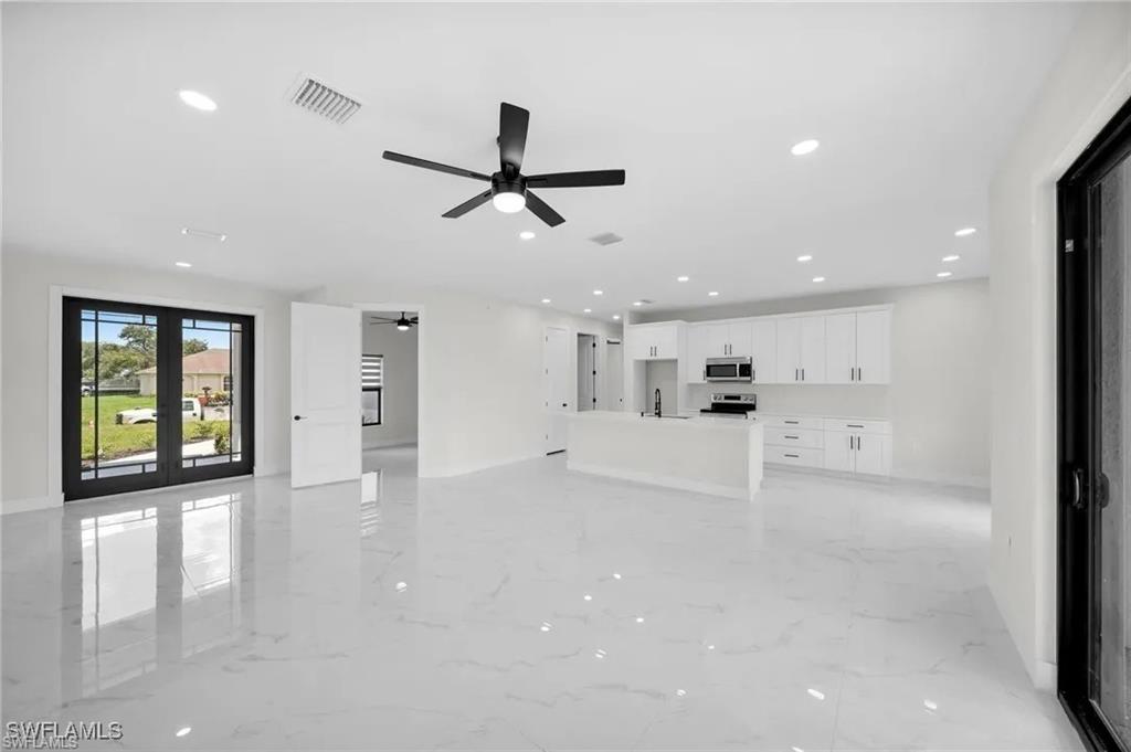 Unfurnished living room featuring recessed lighting, light marble finish flooring, ceiling fan, and french doors