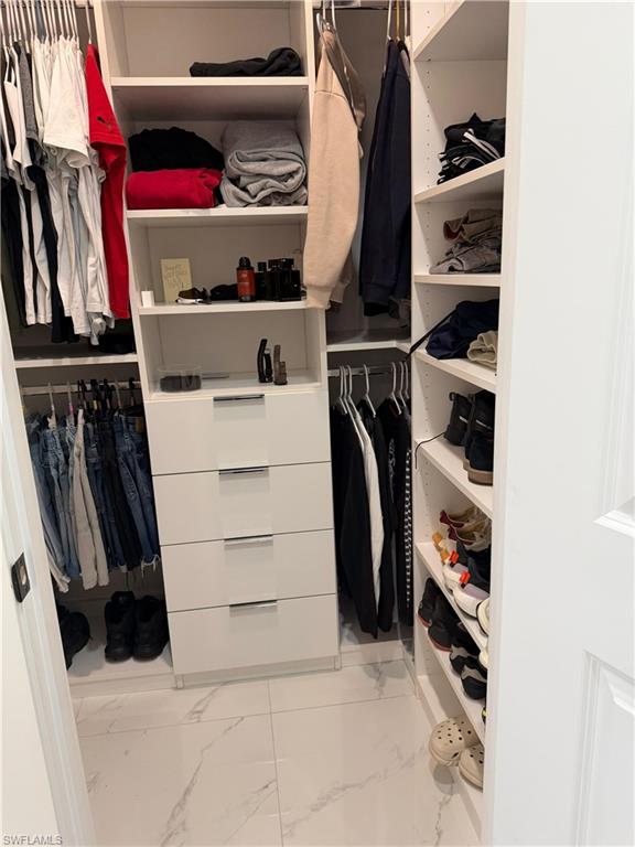 Walk in closet with light marble finish flooring