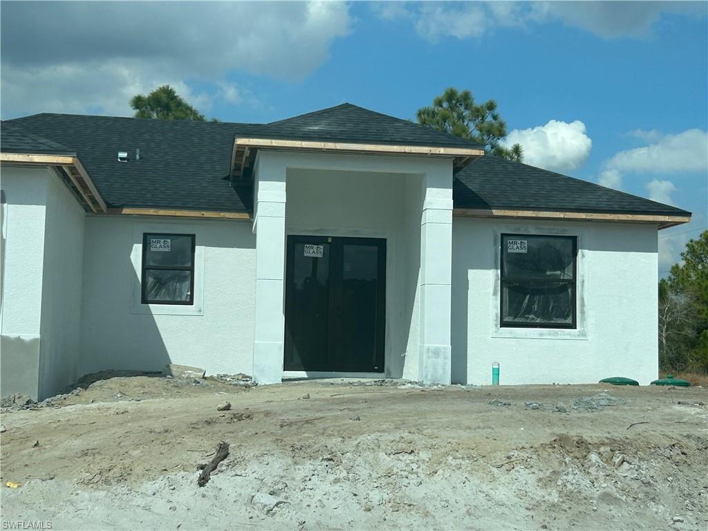 Rear view of property with a shingled roof and stucco siding