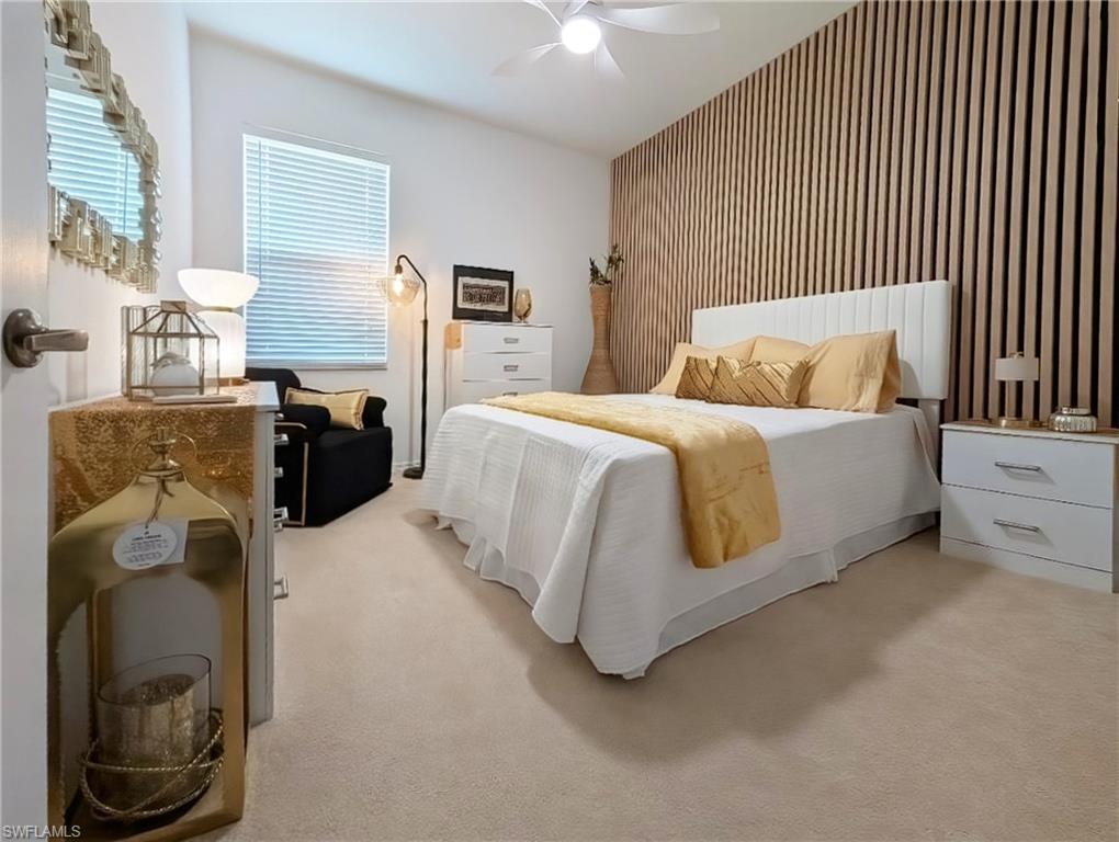 Bedroom with an accent wall, light colored carpet, and ceiling fan