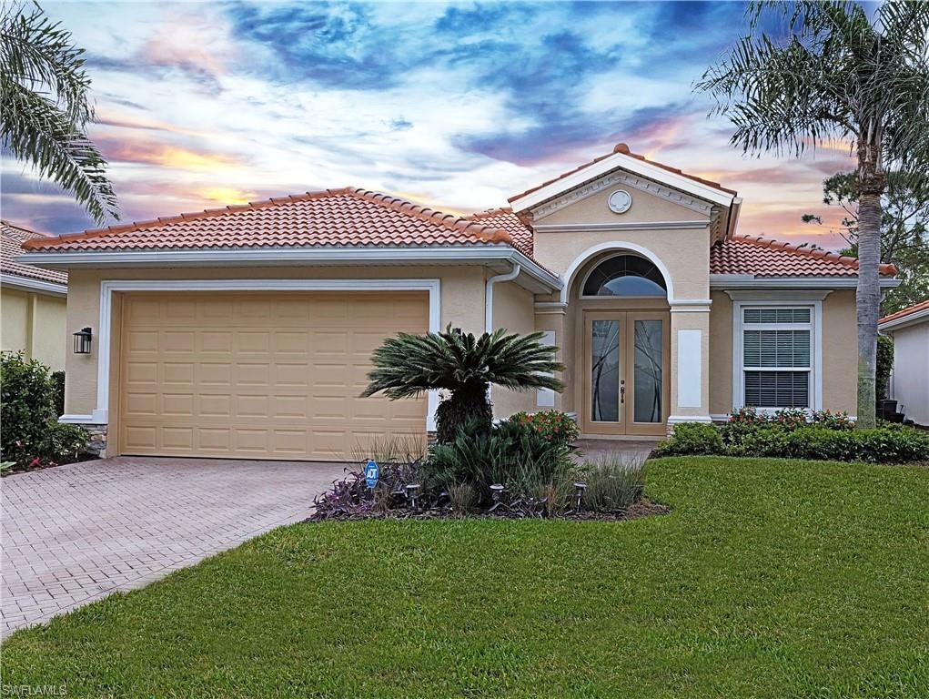 Mediterranean home with a yard, glass French doors, a garage, and stucco siding