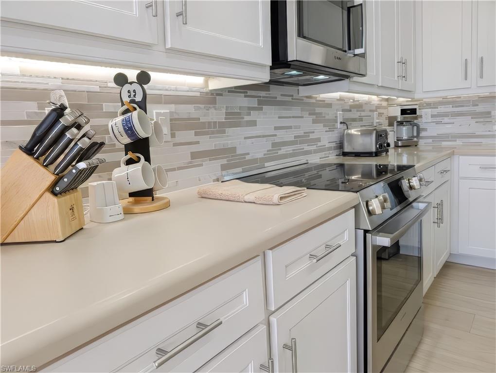 Kitchen featuring tasteful backsplash, white cabinetry, and stainless steel appliances