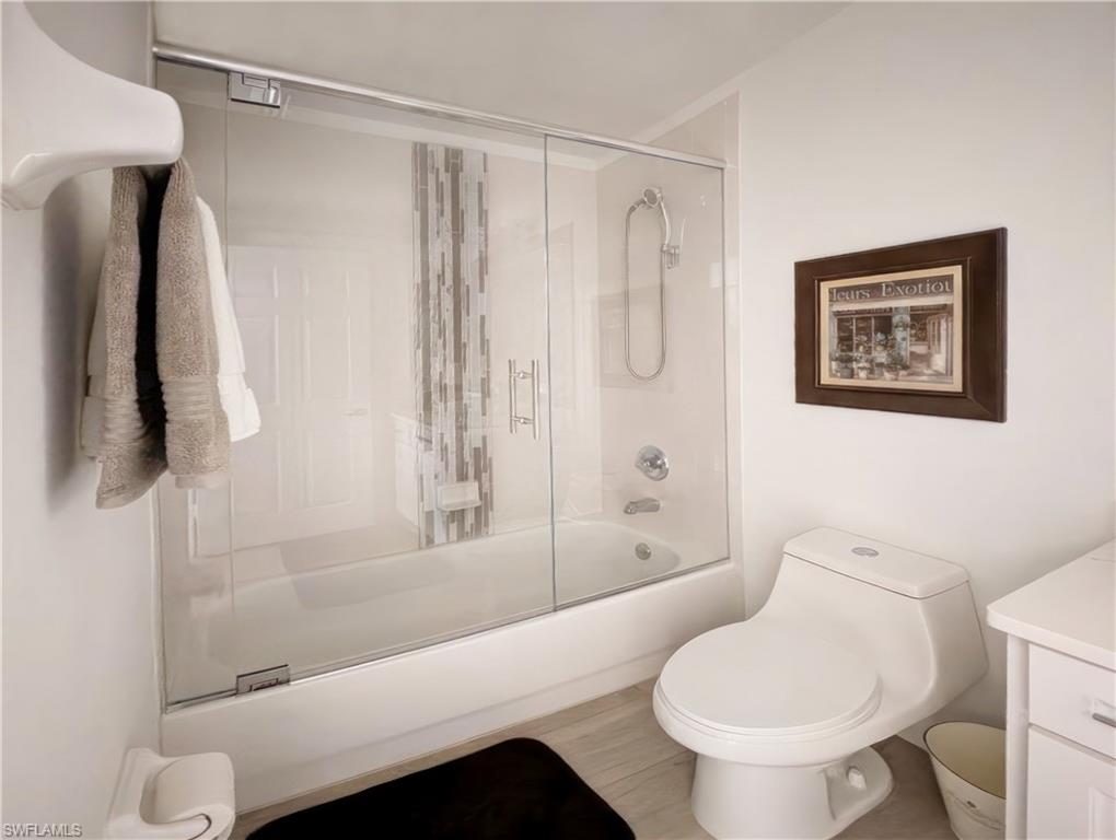 Full bathroom with vanity, bath / shower combo with glass door, and toilet