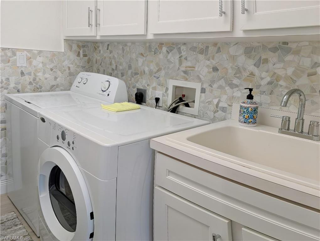 Laundry area featuring cabinets, washing machine and dryer, and sink