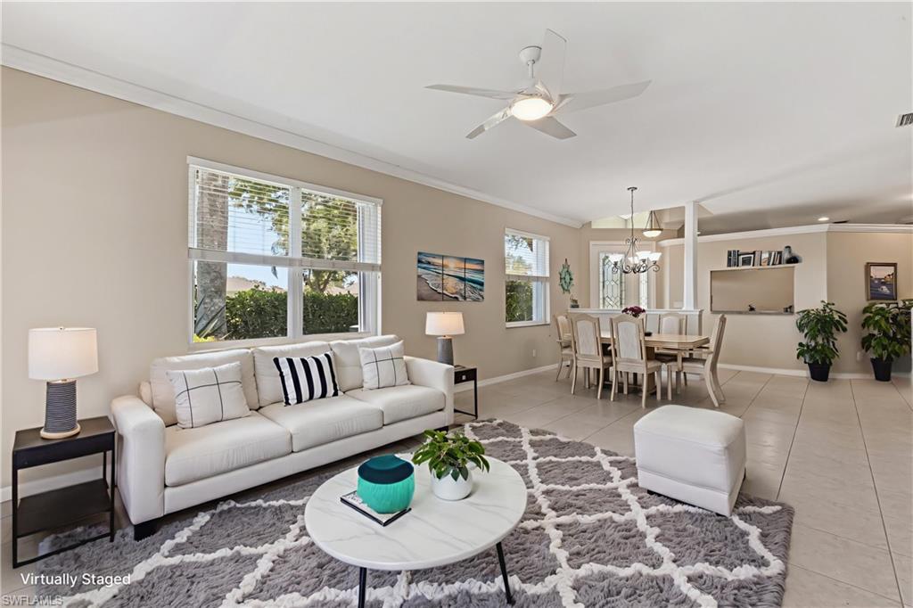 Virtually staged. Open-concept living and dining areas featuring tile flooring, neutral wall tones, multiple windows with blinds, a ceiling fan, and crown molding