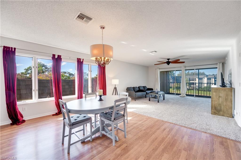 Dining room featuring light wood-style flooring, hanging lights, ceiling fan, and a textured ceiling