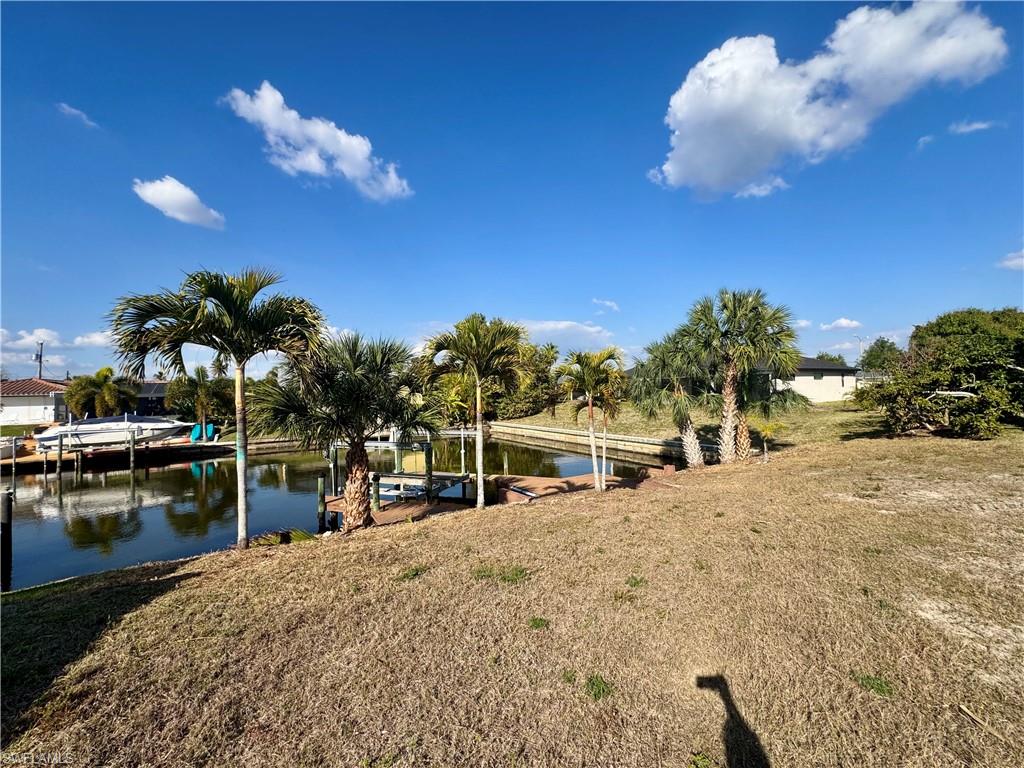 Dock featuring boat lift, a water view, and a yard