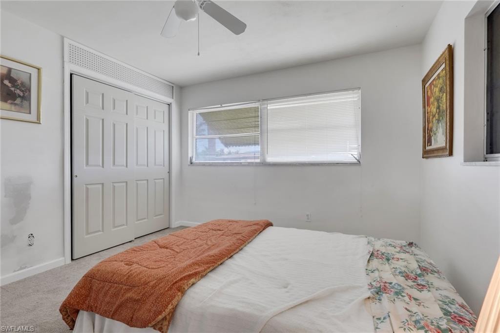 Carpeted bedroom featuring a closet and ceiling fan