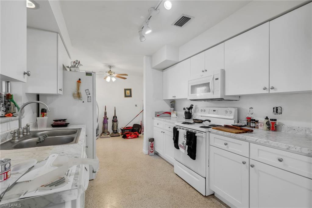 Kitchen featuring white appliances, light countertops, white cabinetry, a ceiling fan, and track lighting