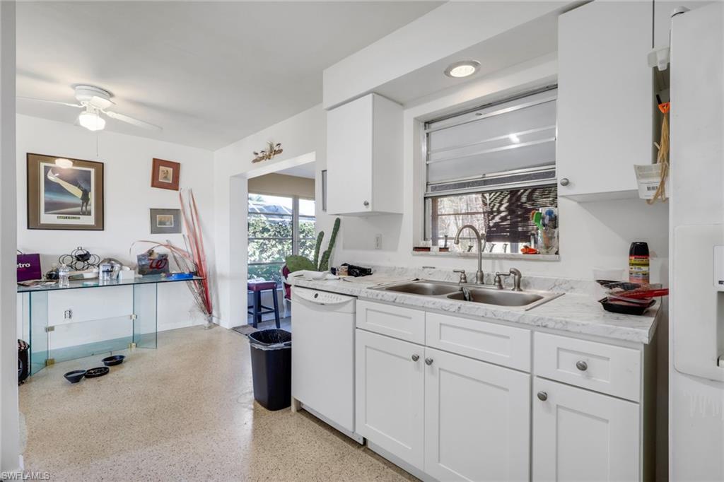 Kitchen with light countertops, white appliances, white cabinets, dark speckled floor, and ceiling fan