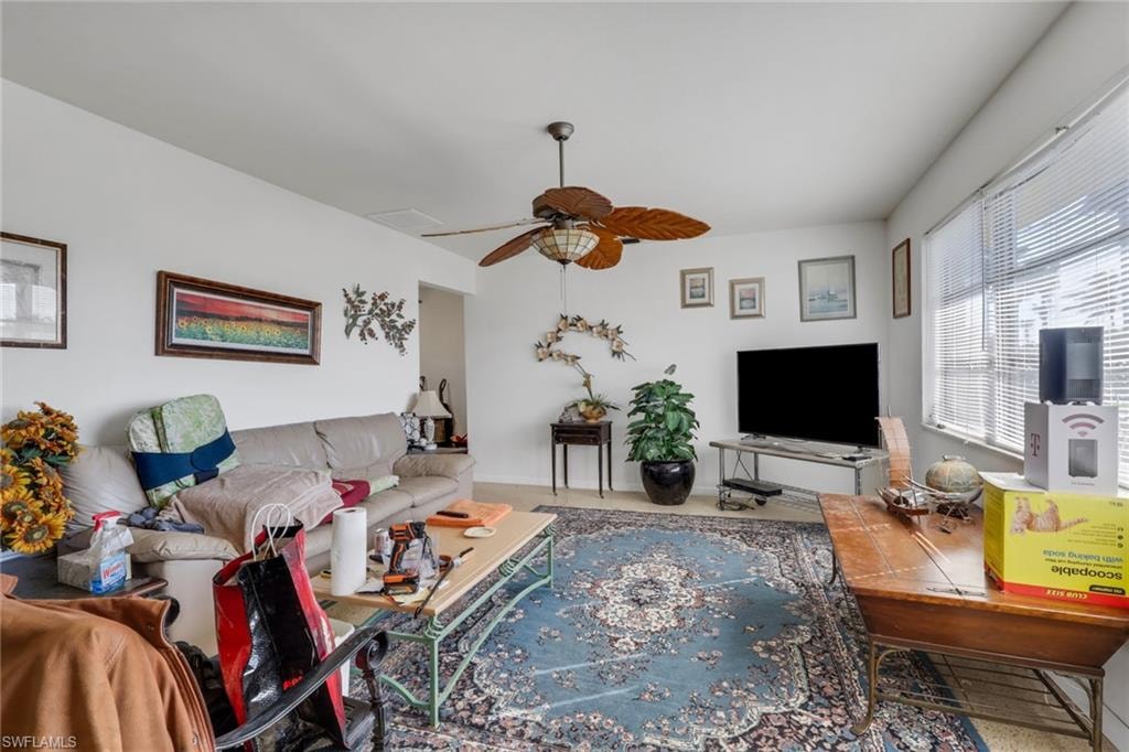 Carpeted living room with a ceiling fan and baseboards