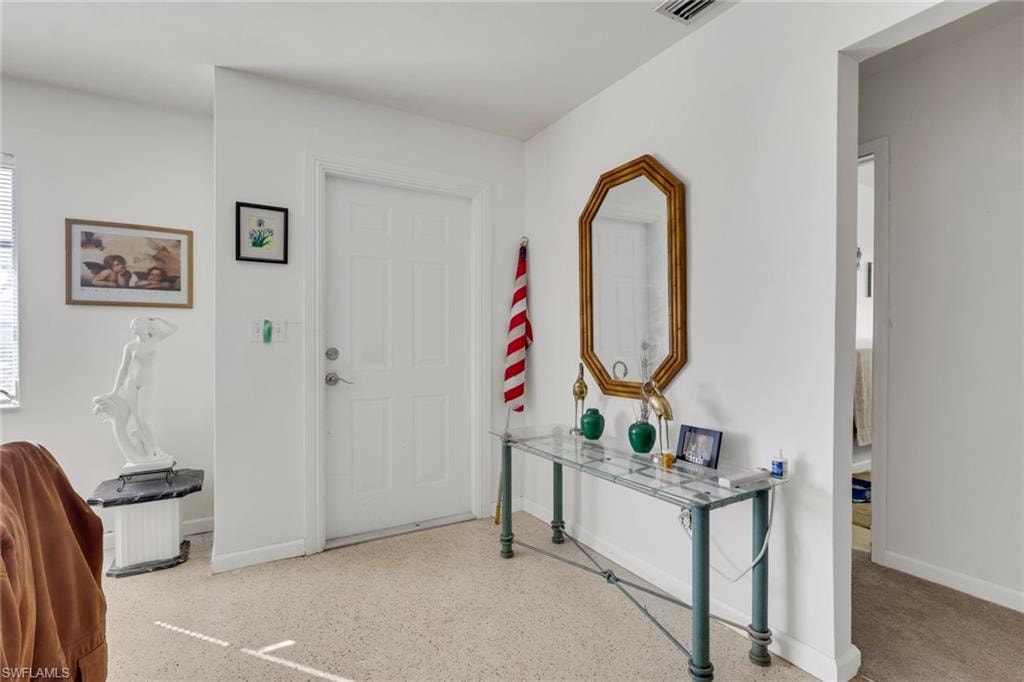 Foyer entrance featuring baseboards and dark speckled floor