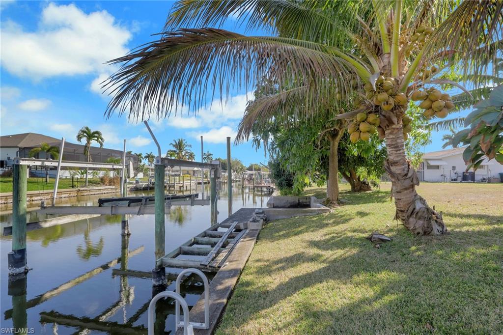 Dock with boat lift, a water view, and a yard