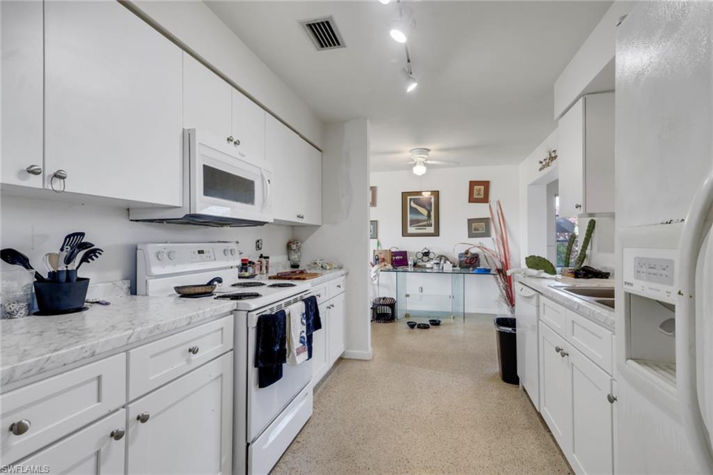 Kitchen featuring white appliances, white cabinets, and dark speckled floor