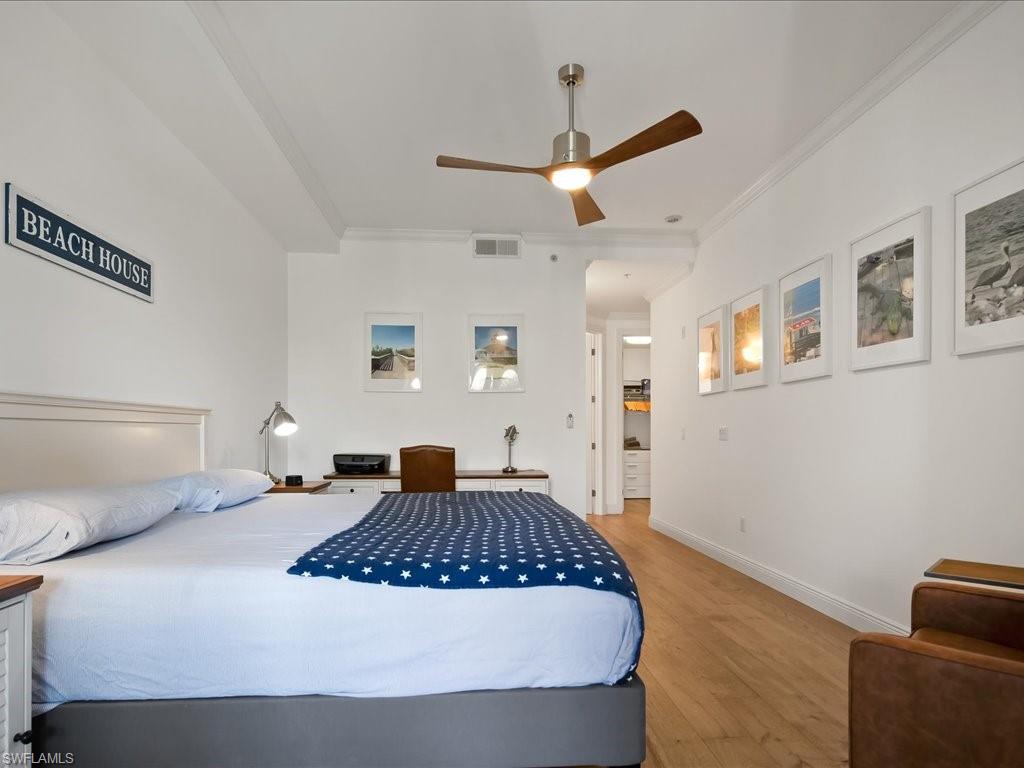 Bedroom featuring wood finished floors, ornamental molding, and ceiling fan