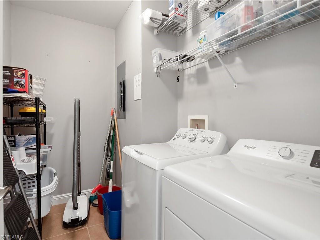 Laundry room featuring light tile patterned flooring, washing machine and clothes dryer, and electric panel