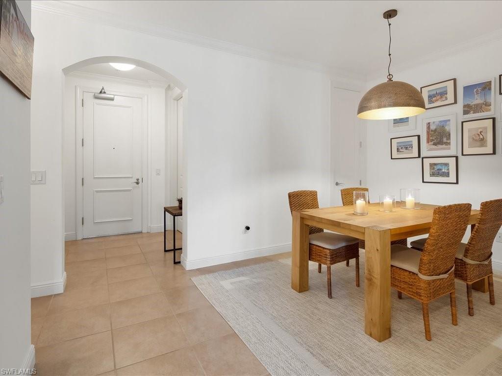 Dining space featuring arched walkways, crown molding, and light tile patterned floors