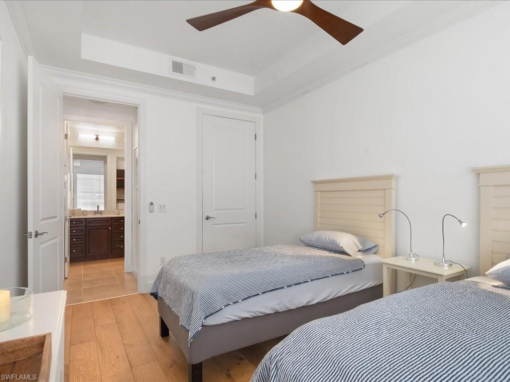 Bedroom featuring a raised ceiling, light wood-style flooring, crown molding, and a ceiling fan