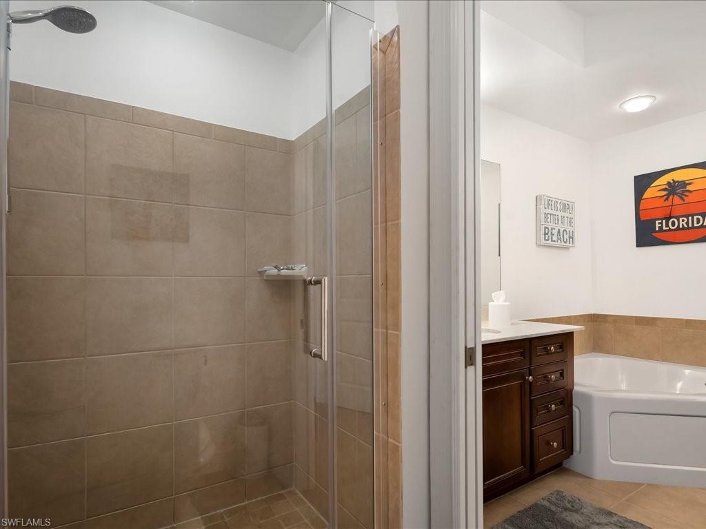 Bathroom with vanity, a shower stall, a bath, and light tile patterned flooring
