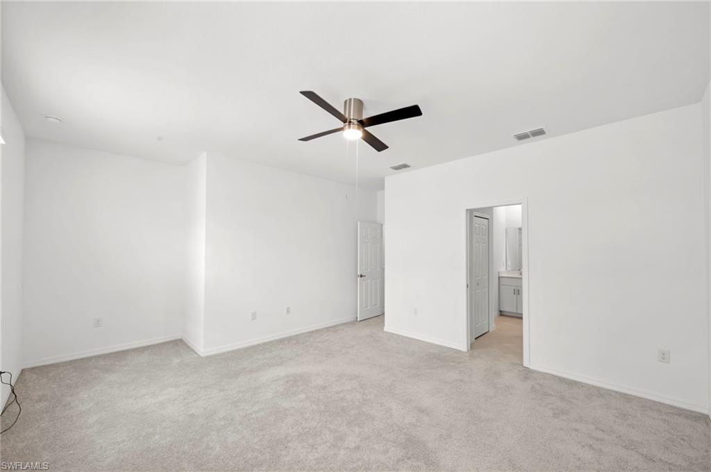 Unfurnished bedroom with light colored carpet and a ceiling fan