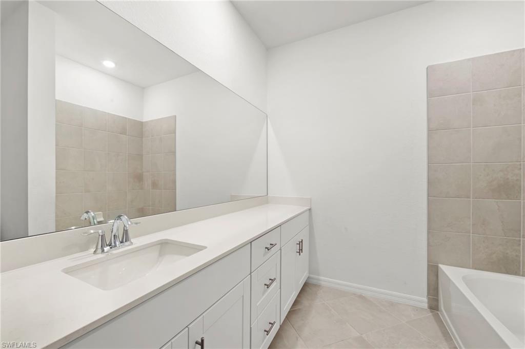 Bathroom featuring vanity, a bath, and light tile patterned floors