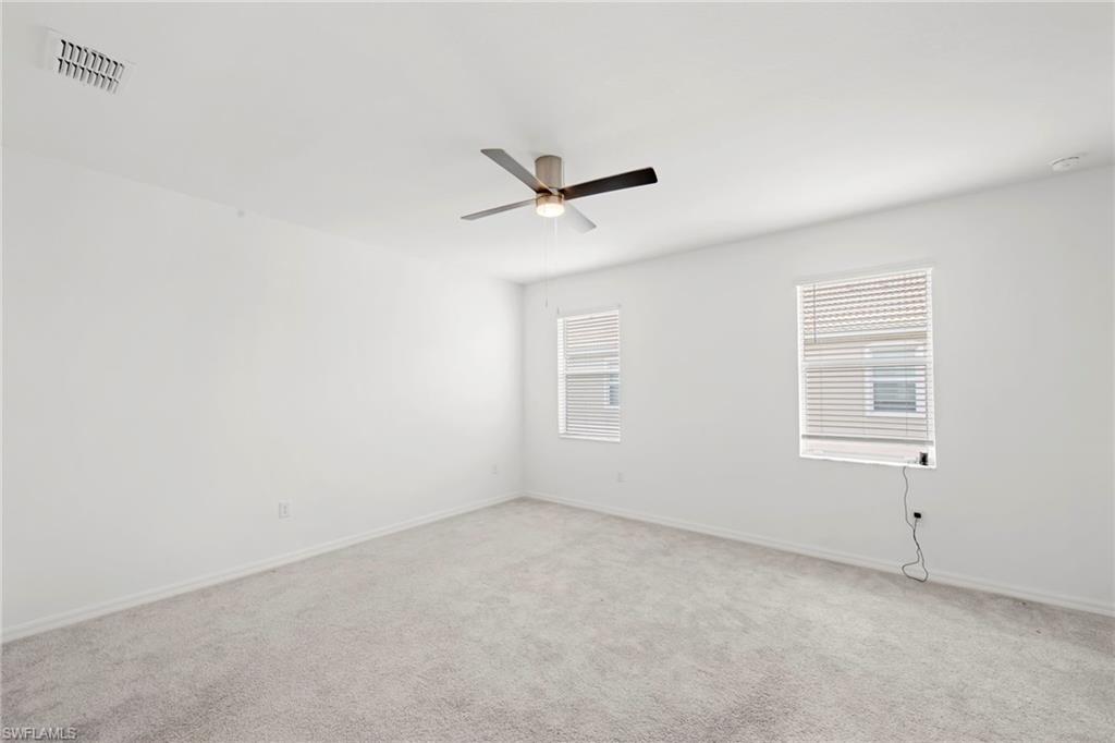 Carpeted empty room featuring baseboards and a ceiling fan