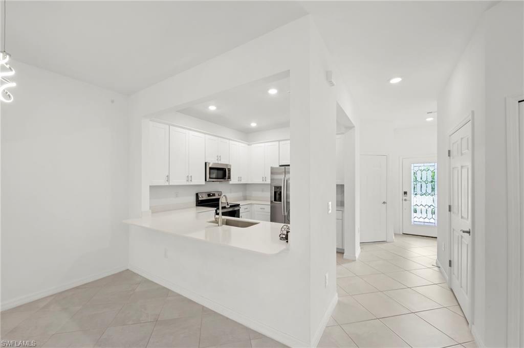 Kitchen featuring a peninsula, white cabinetry, stainless steel appliances, recessed lighting, and light tile patterned floors