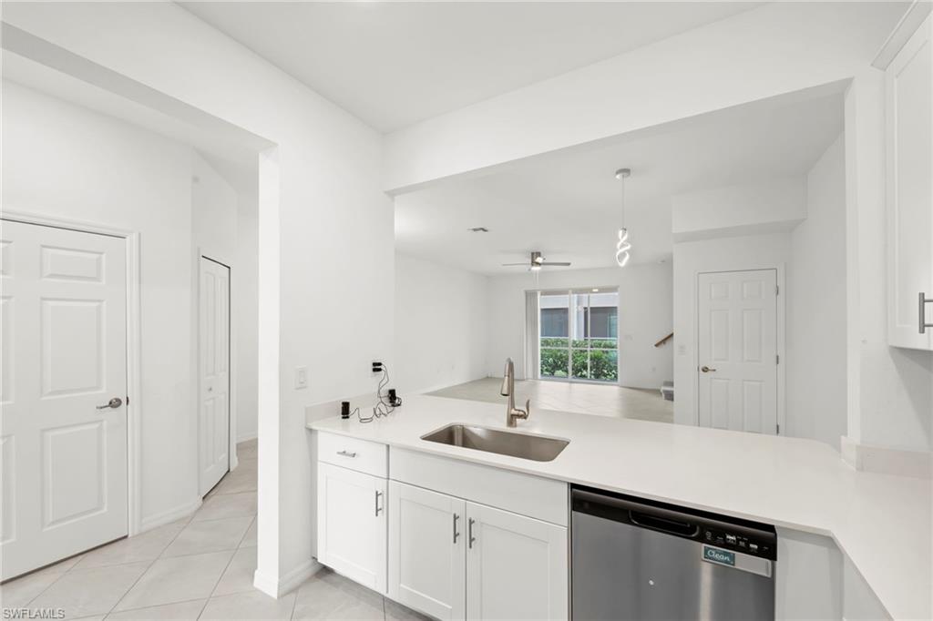 Kitchen featuring a peninsula, dishwasher, white cabinetry, a ceiling fan, and light tile patterned floors