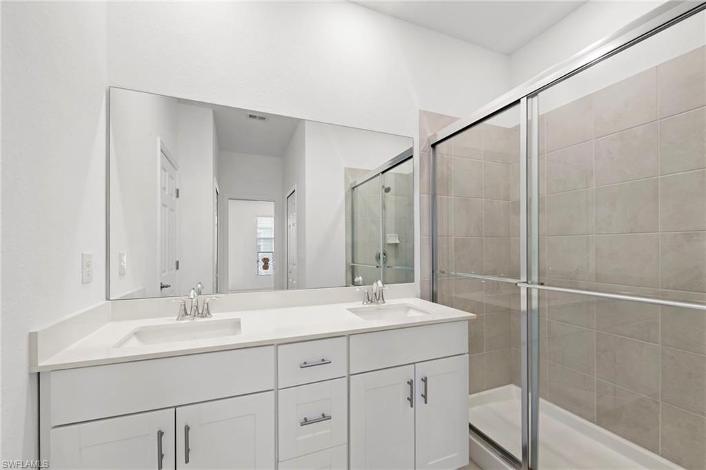 Full bathroom featuring double vanity and a stall shower