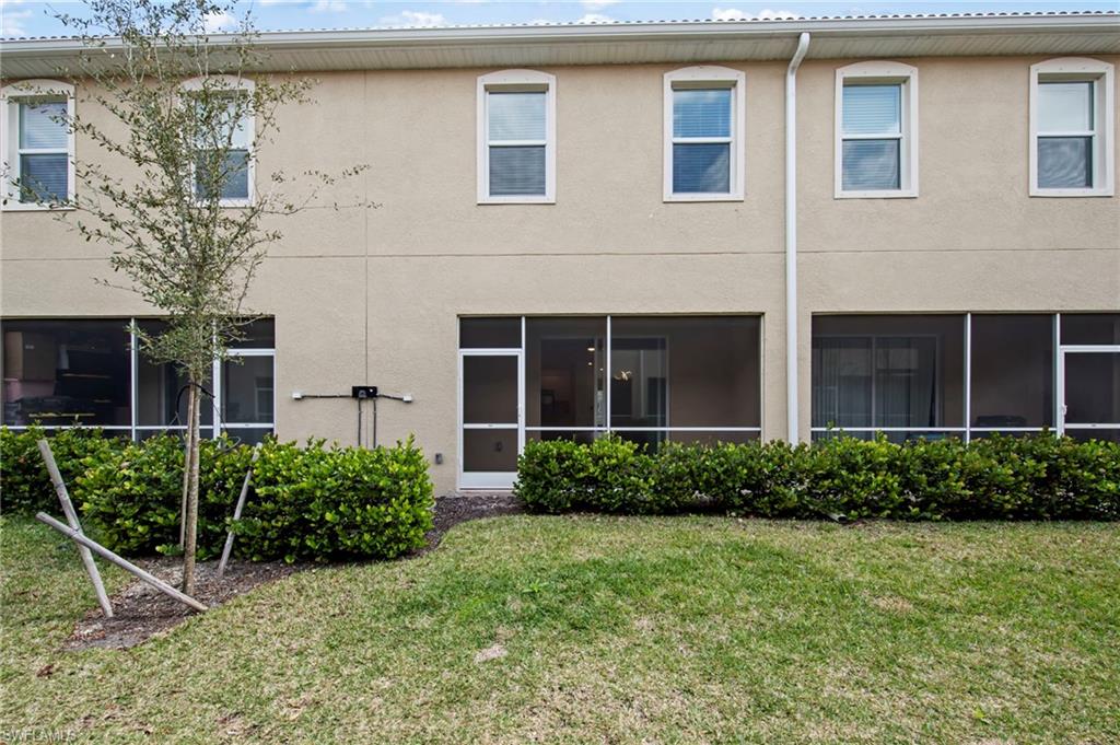 Back of property with a sunroom, stucco siding, and a lawn