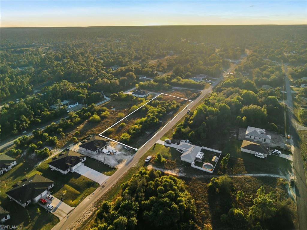 Aerial perspective of suburban area featuring property parcel outlined and a heavily wooded area