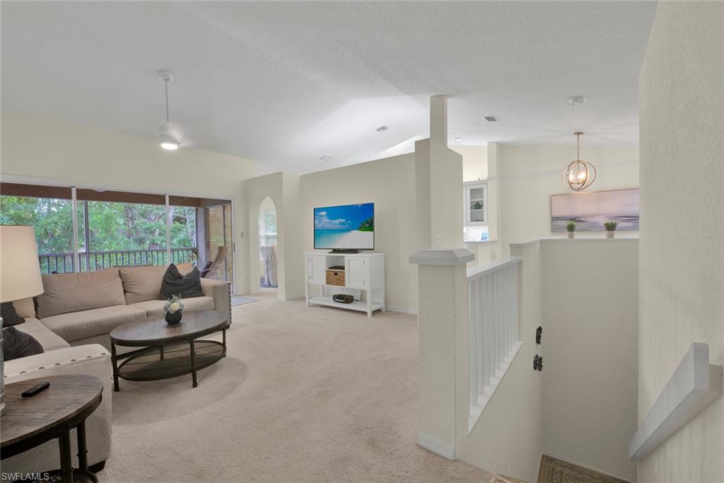 Carpeted living area featuring arched walkways and a high ceiling