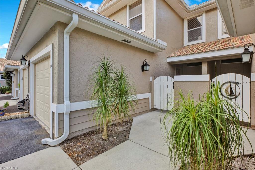View of home's exterior with a gate, stucco siding, a garage, and asphalt driveway