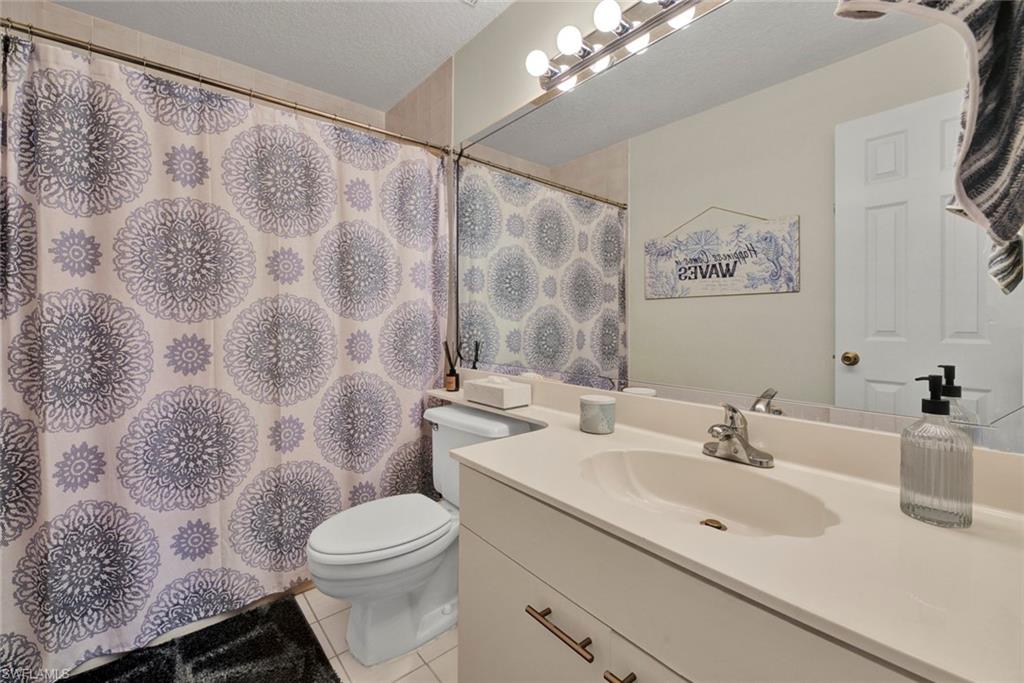 Full bath featuring a shower with curtain, vanity, light tile patterned floors, and a textured ceiling