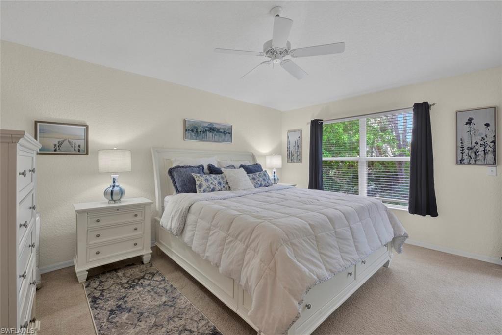 Bedroom featuring light colored carpet, a ceiling fan, and a textured wall