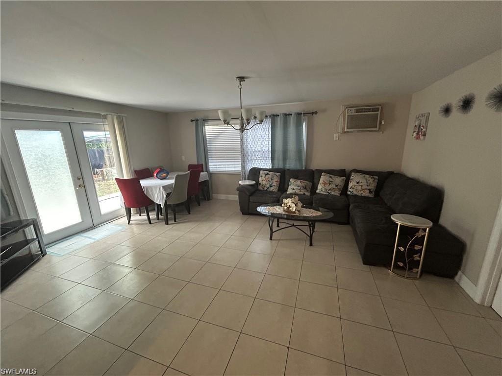Living area with suspended lighting, light tile patterned floors, plenty of natural light, and french doors