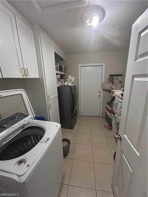 Laundry area featuring light tile patterned floors and cabinet space
