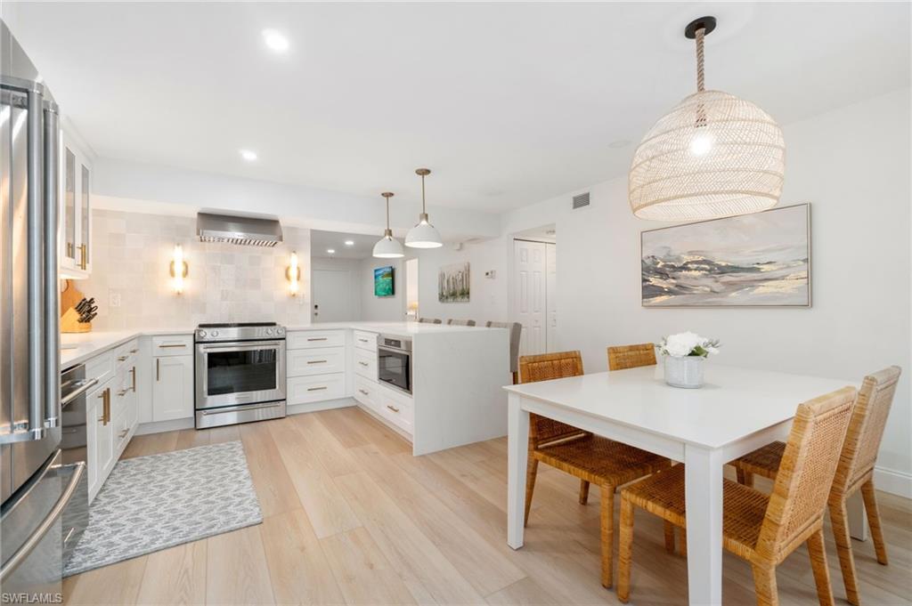 Kitchen featuring pendant lighting, a peninsula, white cabinets, and light stone counters