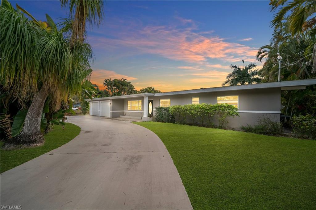 View of front facade featuring stucco siding, a yard, concrete driveway, and a garage