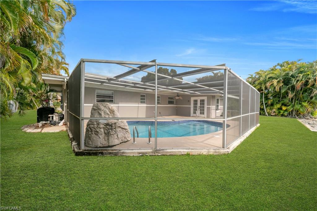 Rear view of property featuring glass enclosure, a sunroom, a yard, an outdoor pool, and a patio area