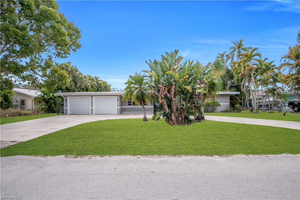 View of front of home with driveway, a front yard, and a garage