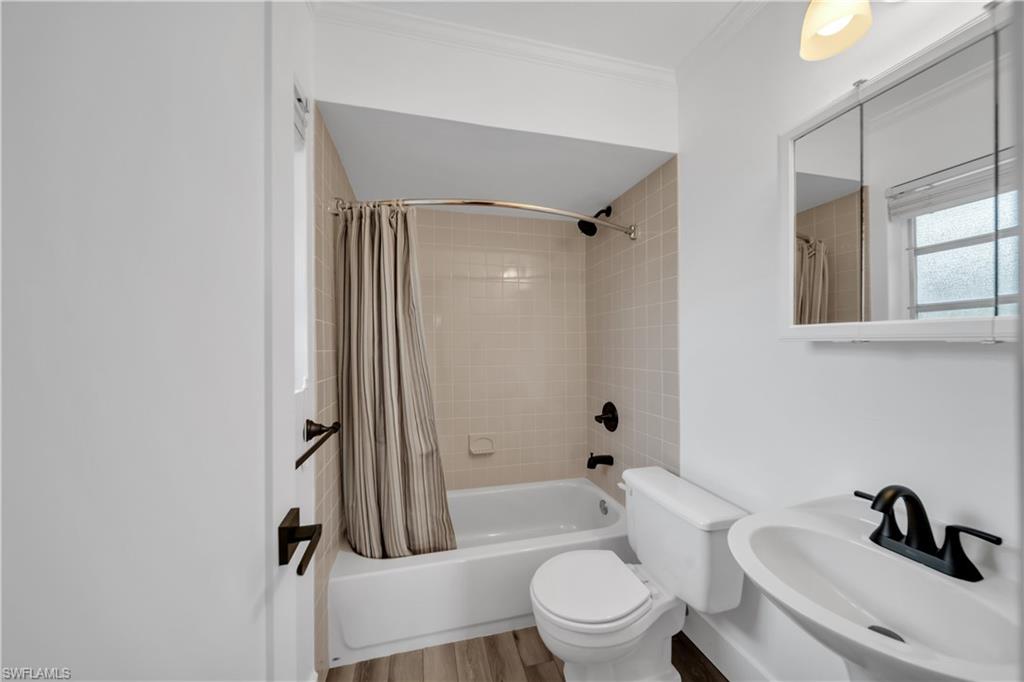 Bathroom featuring shower / bath combo, wood finished floors, and crown molding