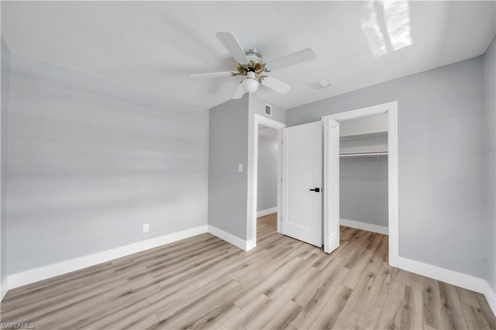 Unfurnished bedroom featuring a spacious closet, light wood-type flooring, and a ceiling fan