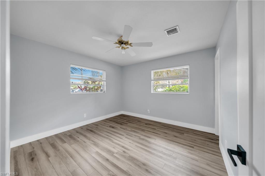 Spare room with light wood-type flooring, a ceiling fan, and healthy amount of natural light