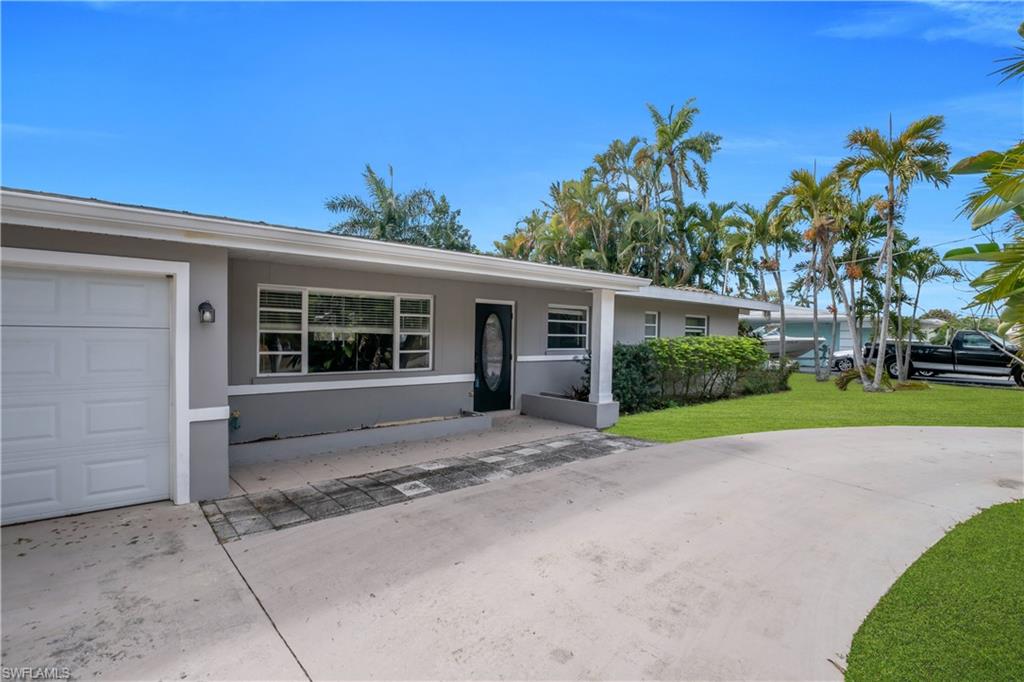 Ranch-style house featuring stucco siding, a front lawn, driveway, and a garage