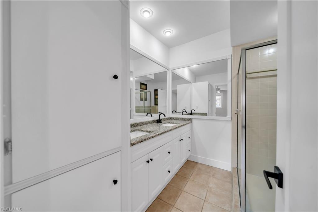 Full bath featuring double vanity, light tile patterned floors, and a shower stall