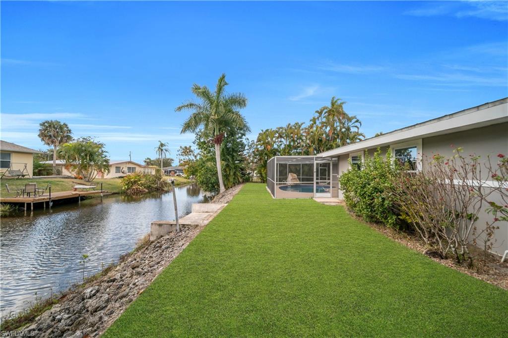 View of green lawn featuring a sunroom, a water view, glass enclosure, an outdoor pool, and a residential view