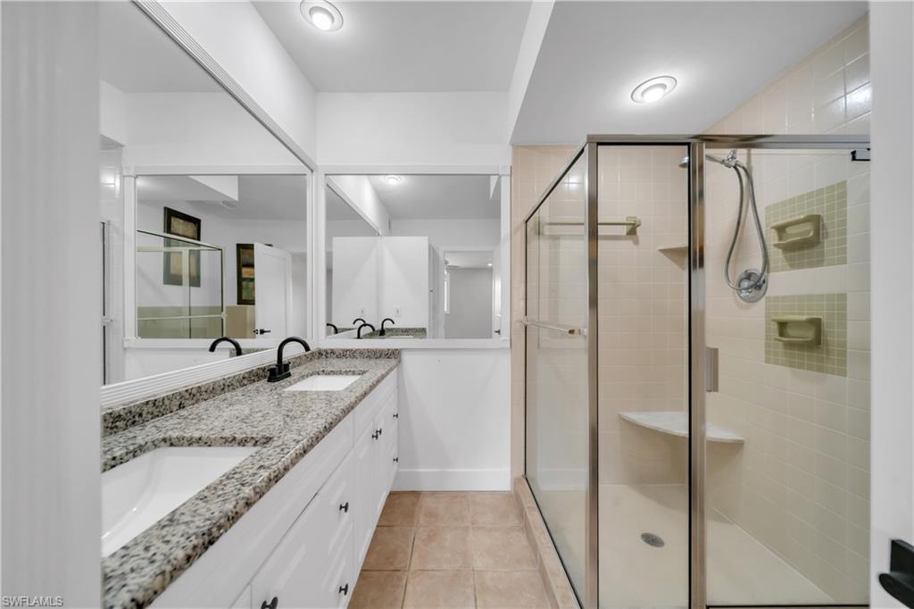 Bathroom with double vanity, a stall shower, and light tile patterned floors